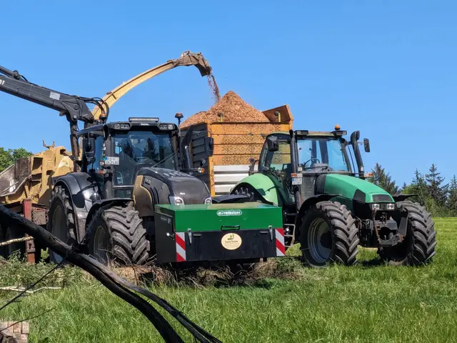 Traktor mit Schild auf einem großen Hackschnitzellager